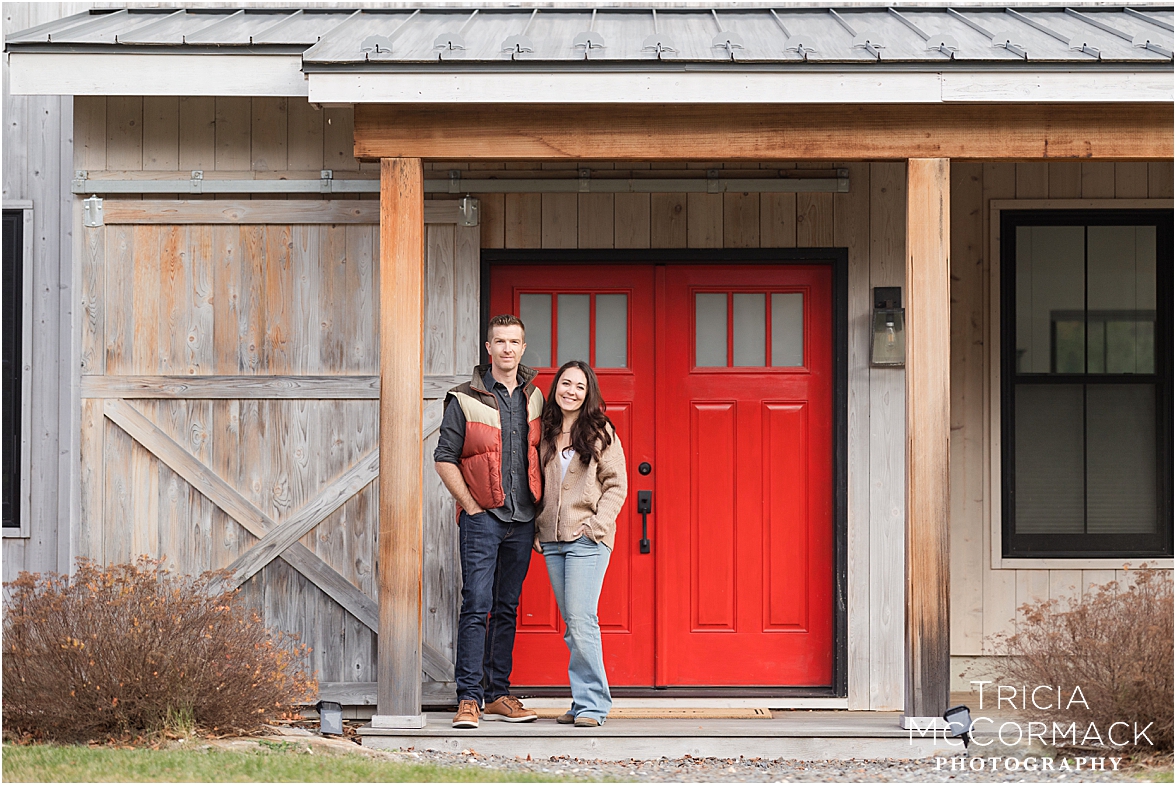 couple stands in front of red door of their rental property